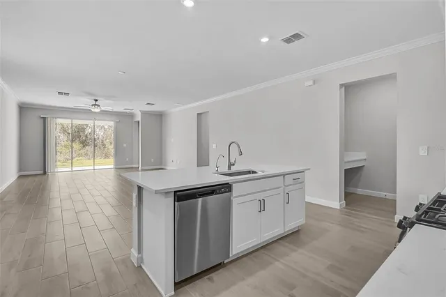 a view of a kitchen with a sink and dishwasher with wooden floor
