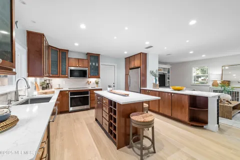 a kitchen with stainless steel appliances granite countertop a stove top oven a sink dishwasher a dining table and chairs with wooden floor