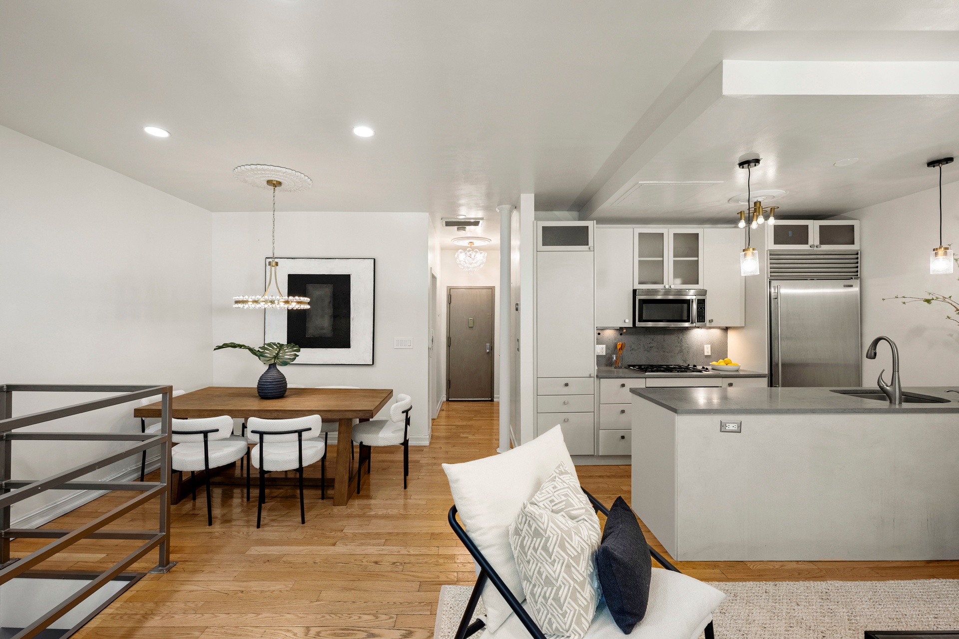 237 East 88th Street, Unit 101 Manhattan, NY 10128 - Photo 5 of 17 a kitchen with stainless steel appliances kitchen island granite countertop a dining table chairs and a refrigerator