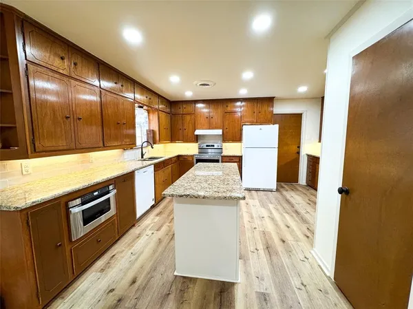 a large kitchen with stainless steel appliances a large counter top a stove and a refrigerator