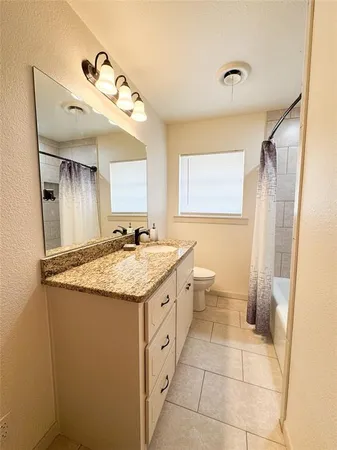 a bathroom with a granite countertop sink a toilet and a mirror
