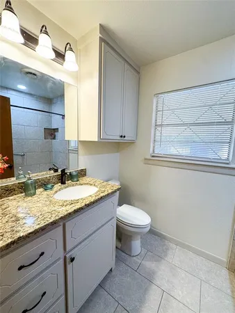 a bathroom with a granite countertop toilet sink and mirror