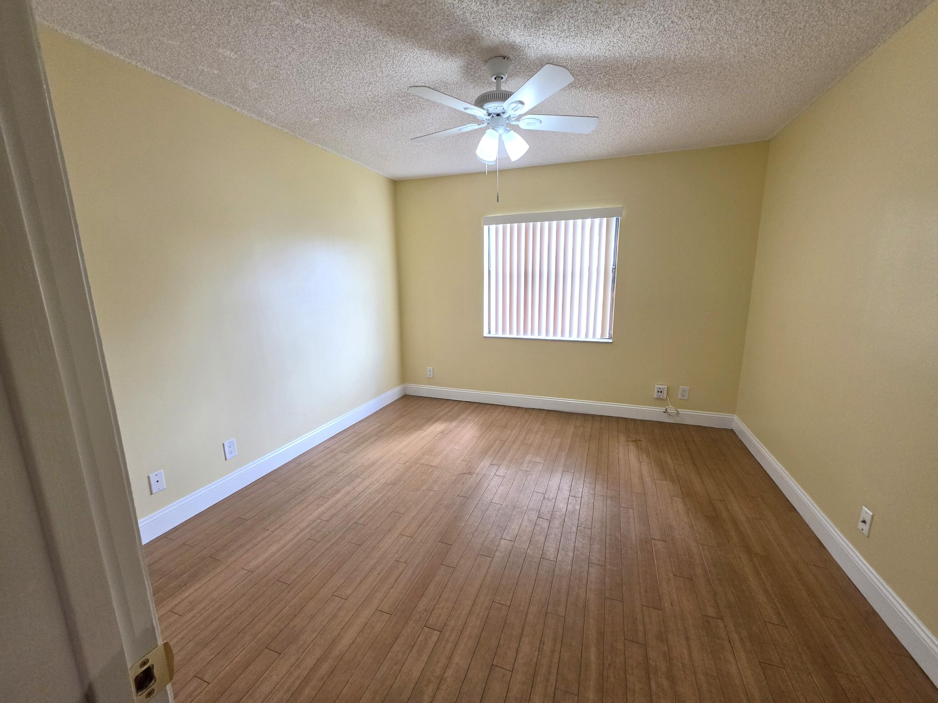 401 Springdale Circle Palm Springs, FL 33461 - Photo 11 of 31 an empty room with wooden floor and windows