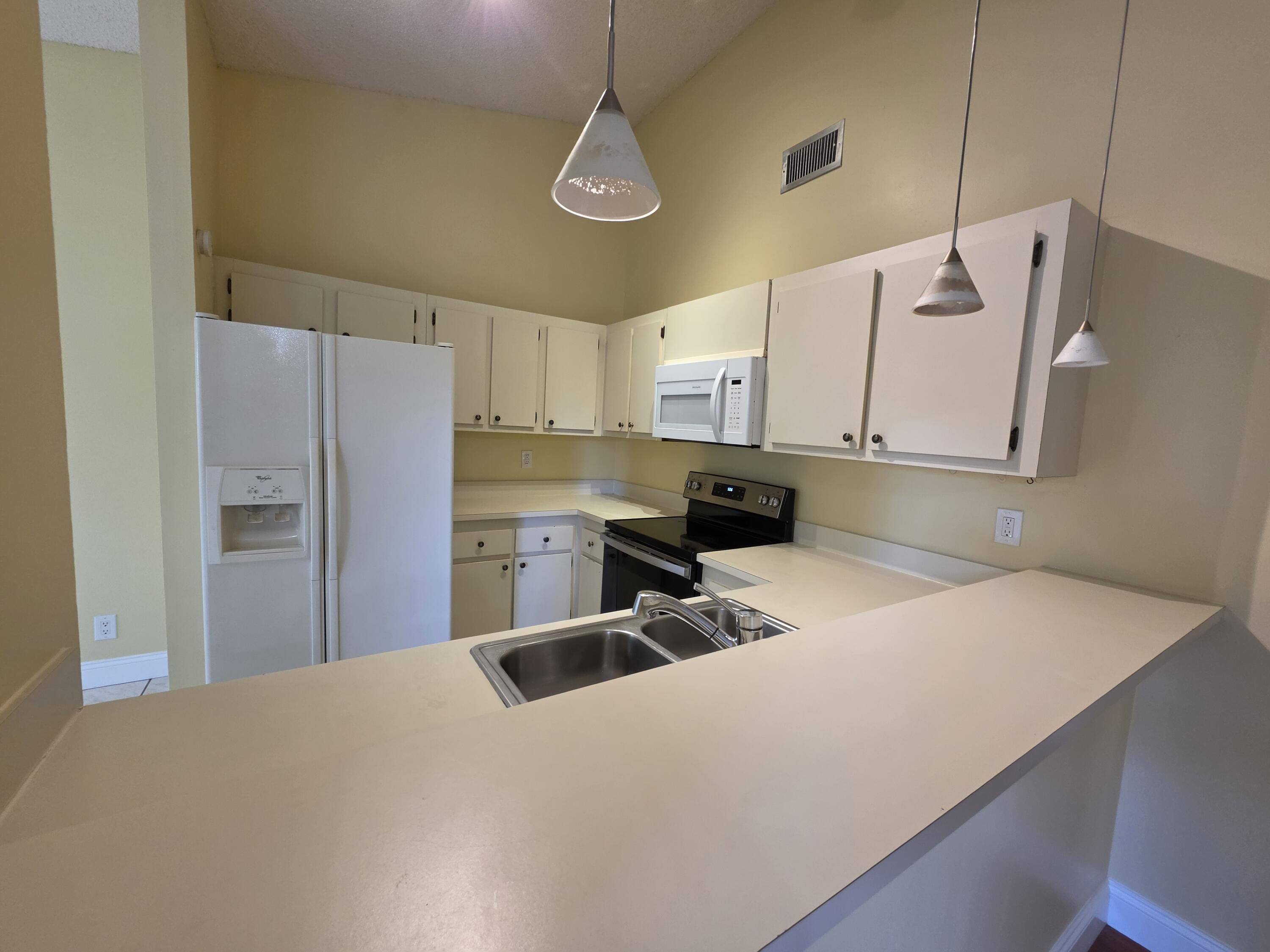 401 Springdale Circle Palm Springs, FL 33461 - Photo 8 of 31 a kitchen with stainless steel appliances a refrigerator a stove a sink and white cabinets
