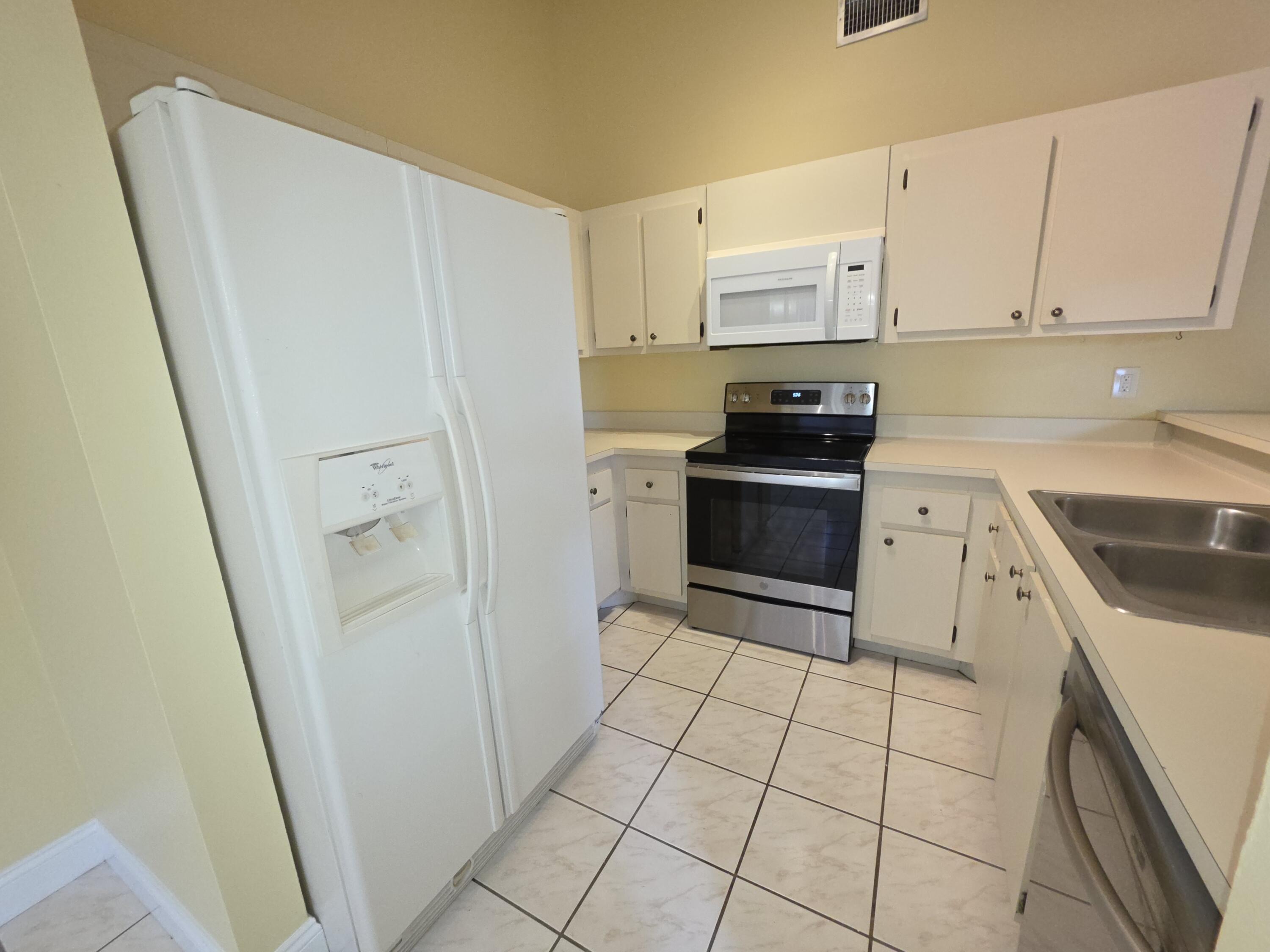 401 Springdale Circle Palm Springs, FL 33461 - Photo 10 of 31 a kitchen with a stove a refrigerator and a sink