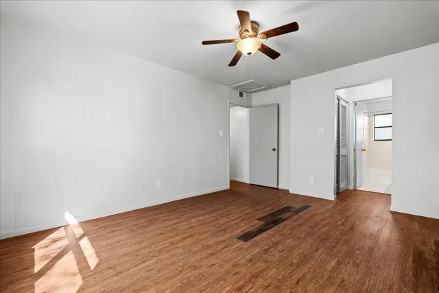 a view of a big room with wooden floor and a chandelier fan