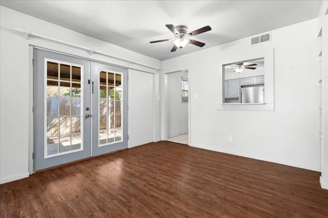 a view of an empty room with a window and wooden floor