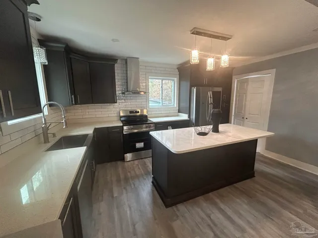 a large kitchen with kitchen island a sink stainless steel appliances and a large window