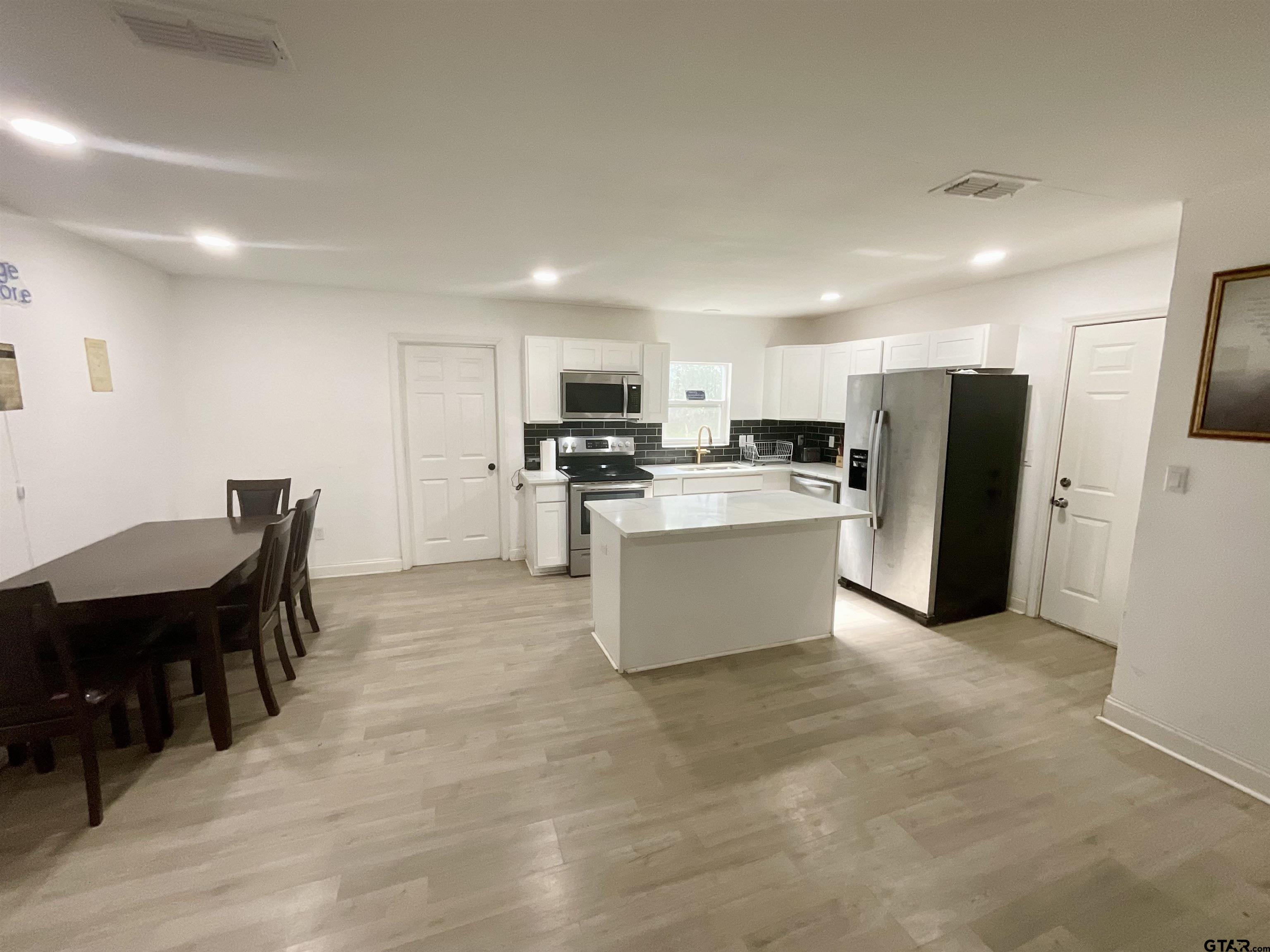 151 Patton Lane Tyler, TX 75704 - Photo 6 of 26 a large kitchen with kitchen island a dining table chairs and a refrigerator