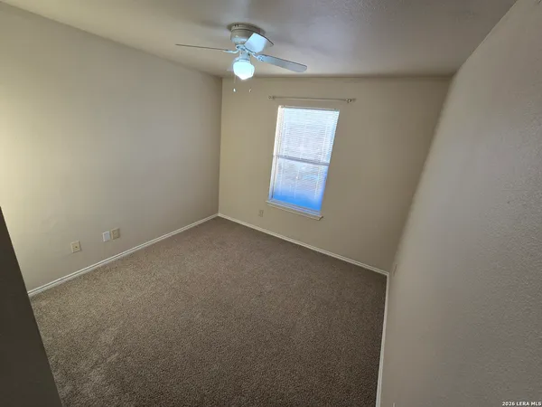 an empty room with closet and a chandelier fan