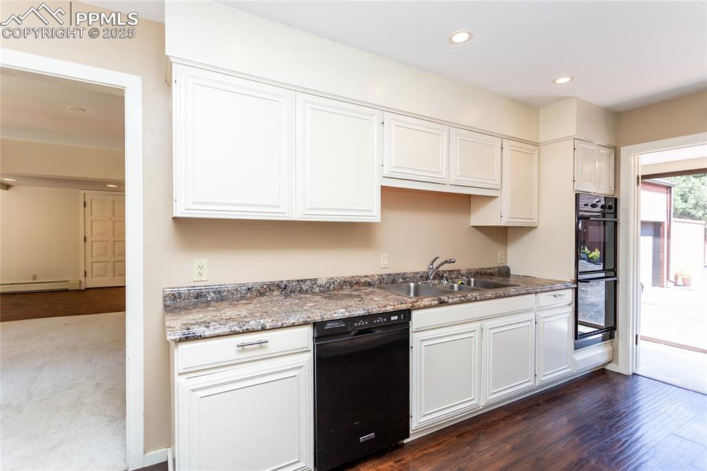 2650 Spring Grove Terrace Colorado Springs, CO 80906 - Photo 11 of 35 Kitchen with recessed lighting, dark wood-type flooring, white cabinets, dark countertops, and a baseboard heating unit