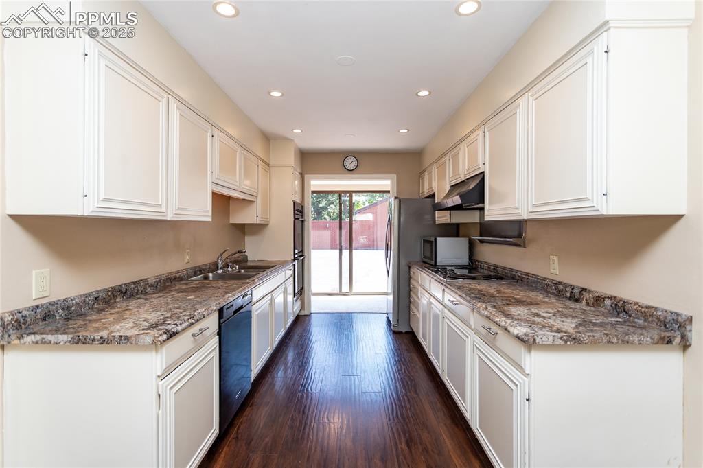 2650 Spring Grove Terrace Colorado Springs, CO 80906 - Photo 10 of 35 Kitchen featuring recessed lighting, white cabinetry, dark countertops, and dark wood-style flooring