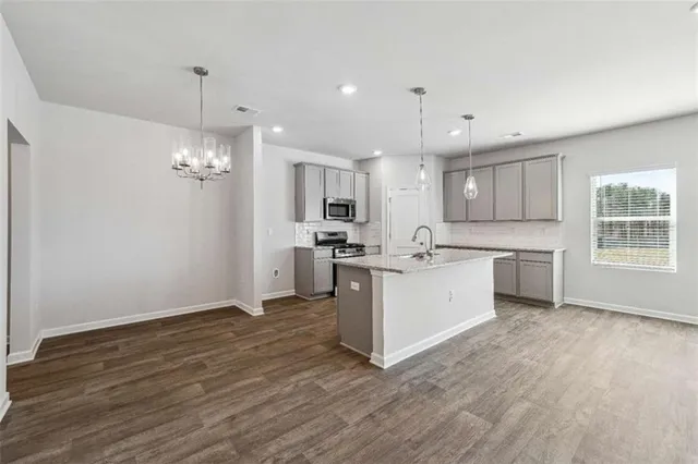 a large white kitchen with a refrigerator a sink dishwasher a stove and white cabinets with wooden floor