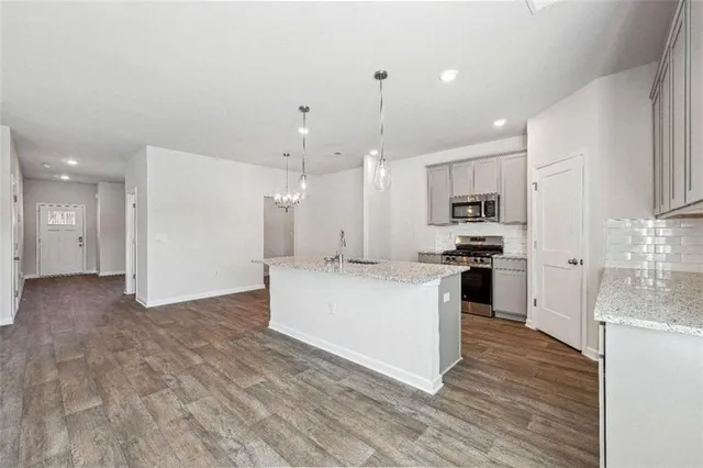 a large kitchen with kitchen island a sink a stove a refrigerator and white cabinets