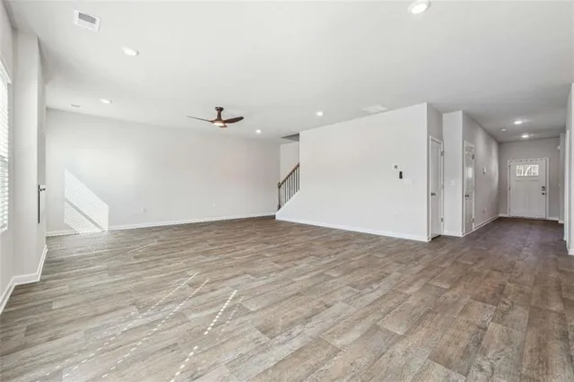 an empty room with wooden floor and a ceiling fan