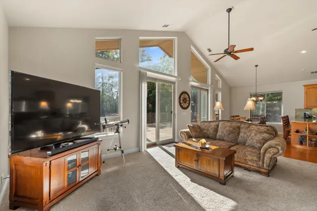 a living room with furniture a flat screen tv and a floor to ceiling window
