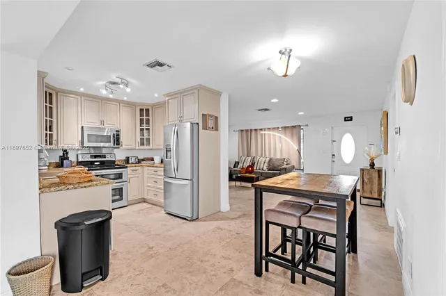 a kitchen with stainless steel appliances granite countertop a refrigerator stove microwave and sink