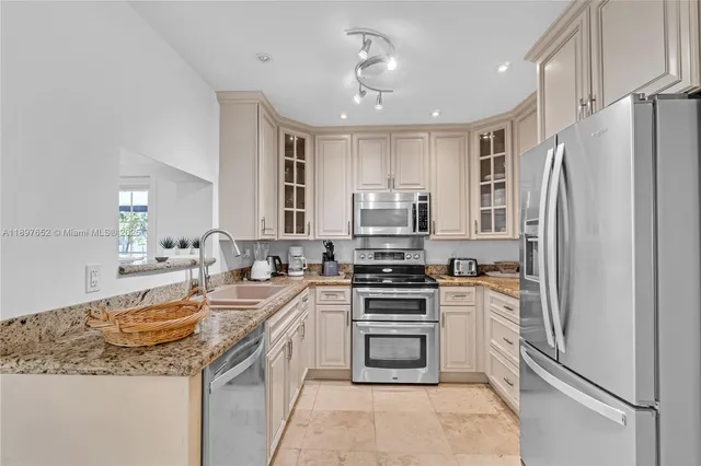 a kitchen with stainless steel appliances granite countertop a sink stove oven and white cabinets