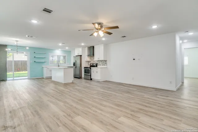a view of an empty room with kitchen and kitchen view