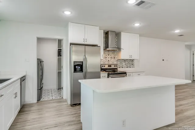 a kitchen with kitchen island a sink appliances and cabinets