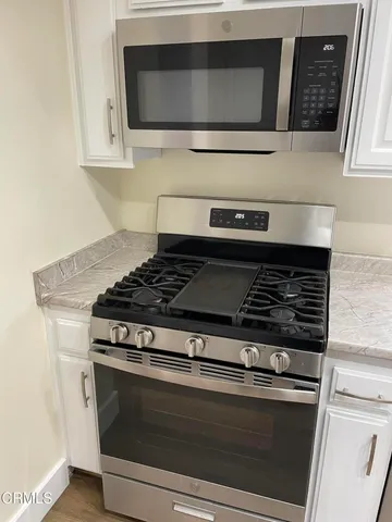 a kitchen with granite countertop white cabinets and a white stove
