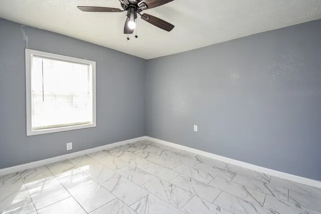 an empty room with a ceiling fan and wooden floor