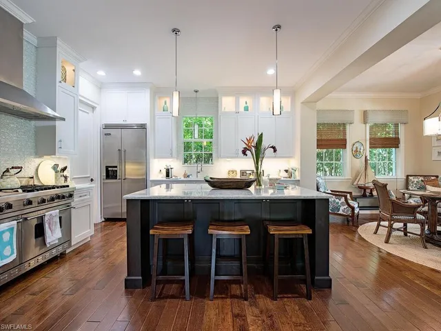 a kitchen with granite countertop a stove a sink a dining table and chairs with wooden floor