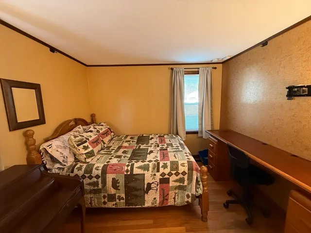a bedroom with a bed and a dresser next to a window