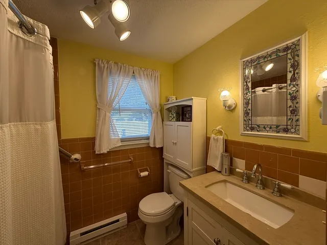 a bathroom with a granite countertop toilet sink and mirror
