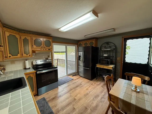 a kitchen with stainless steel appliances granite countertop a refrigerator a stove a sink dishwasher and wooden cabinets with wooden floor