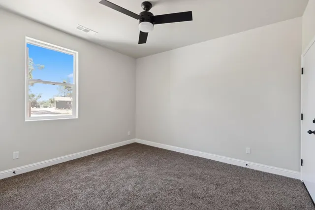 an empty room with a window and a fan
