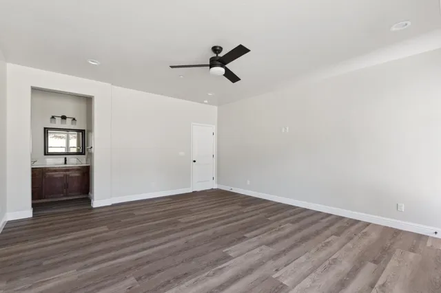 an empty room with wooden floor cabinet and windows