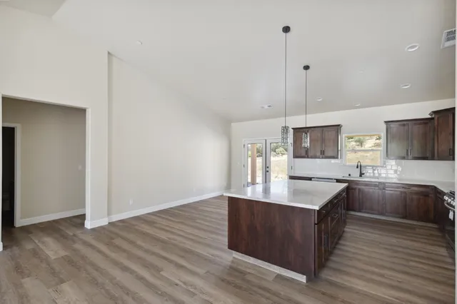 a large kitchen with stainless steel appliances a large counter top a stove and a wooden floors