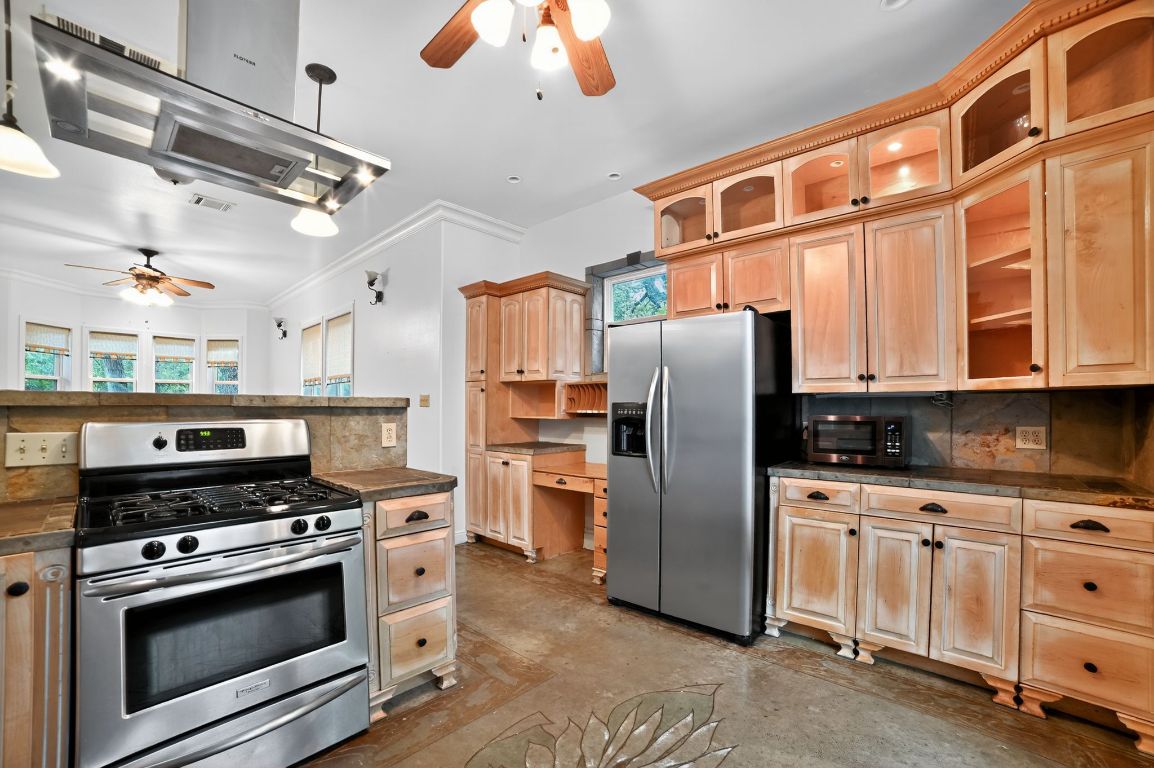 2003 Griswold Lane, Unit A Austin, TX 78703 - Photo 14 of 21 Kitchen featuring ceiling fan, stainless steel appliances, exhaust hood, dark countertops, and ornamental molding