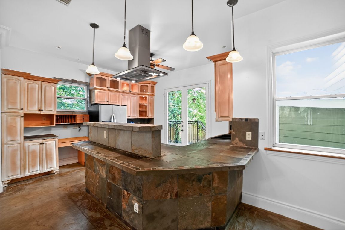2003 Griswold Lane, Unit A Austin, TX 78703 - Photo 15 of 21 Kitchen with open shelves, island exhaust hood, freestanding refrigerator, a ceiling fan, and a peninsula