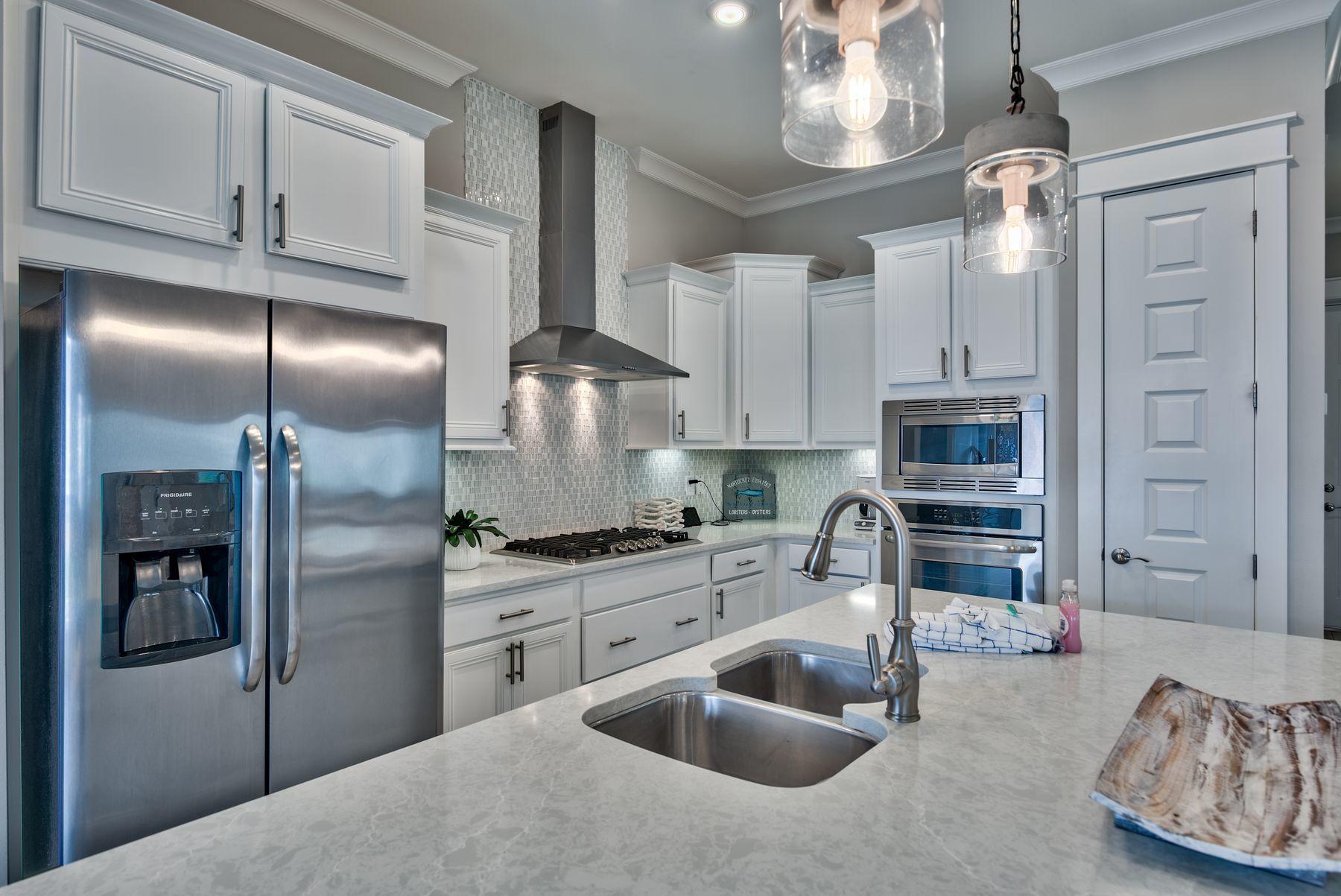 35 Milestone Dr Inlet Beach, Unit A Inlet Beach, FL 32461 - Photo 10 of 31 a kitchen with stainless steel appliances granite countertop a refrigerator a sink a stove and chairs with wooden floor