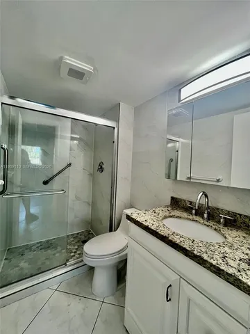 a bathroom with a granite countertop sink a toilet and shower