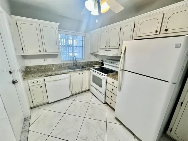 a kitchen with white cabinets and white appliances