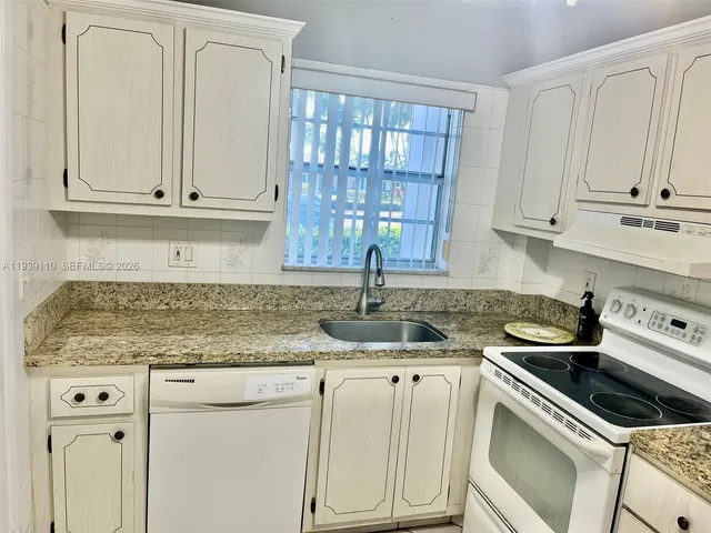 a kitchen with granite countertop white cabinets and a sink