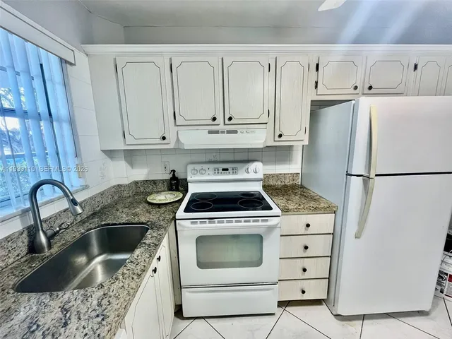 a kitchen with granite countertop a sink stove and refrigerator