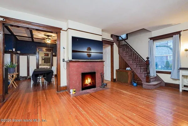 a view of an empty room with wooden floor fireplace and a window