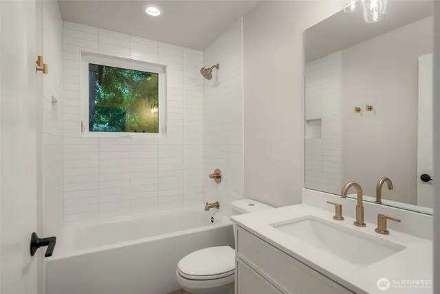 a bathroom with a granite countertop bathtub shower sink vanity mirror and toilet