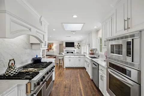 a large kitchen with stainless steel appliances granite countertop a stove and a sink