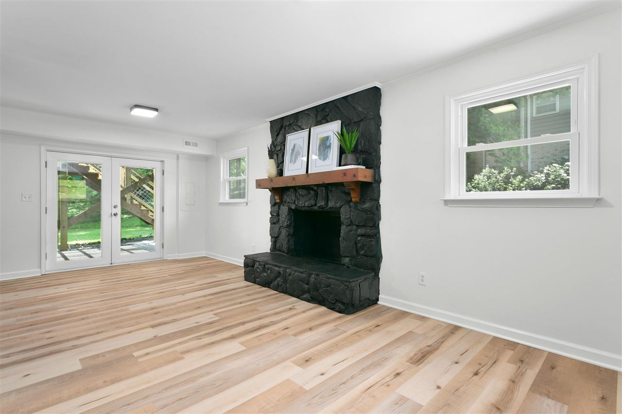 6816 Valley Drive Raleigh, NC 27612 - Photo 12 of 30 Wood burning fireplace and access to a patio and a spacious and shaded backyard. Lower Level Living/Family Room
