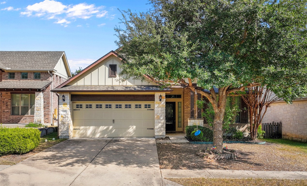 View of front of property featuring stone siding, board and batten siding, driveway, and a garage