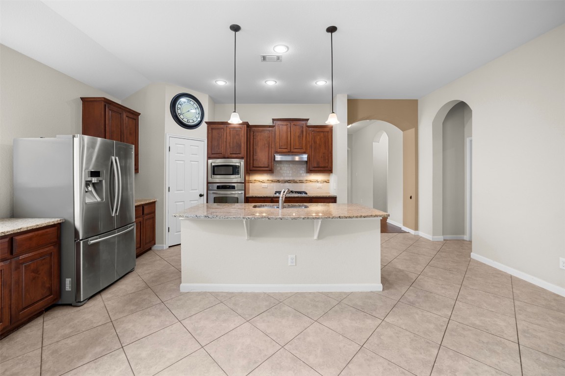 216 Archipelago Trail Austin, TX 78717 - Photo 12 of 40 Kitchen featuring backsplash, stainless steel appliances, a kitchen bar, light tile patterned floors, and recessed lighting