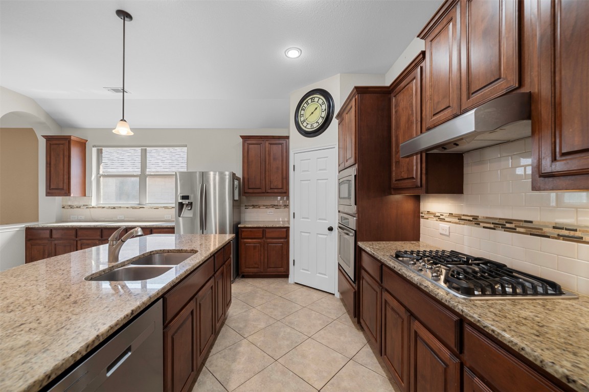 216 Archipelago Trail Austin, TX 78717 - Photo 14 of 40 Kitchen featuring backsplash, hanging light fixtures, stainless steel appliances, light stone countertops, and recessed lighting