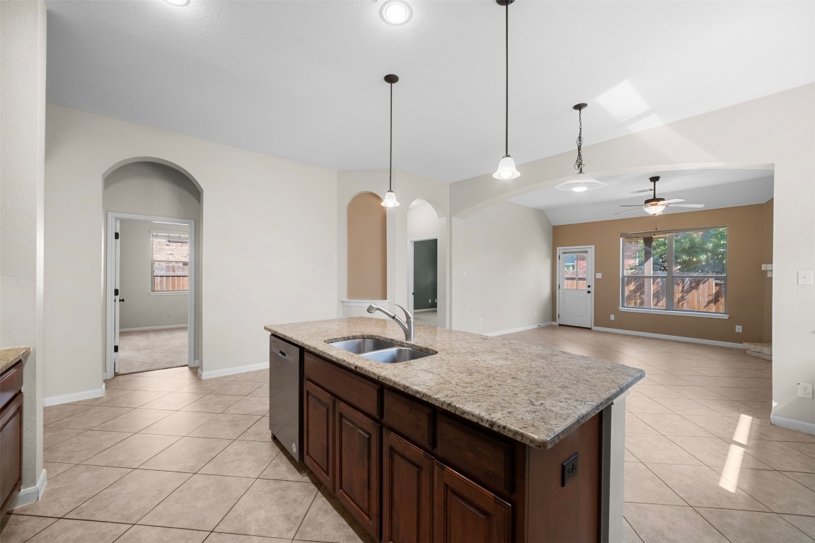 216 Archipelago Trail Austin, TX 78717 - Photo 40 of 40 Kitchen featuring dark brown cabinetry, decorative light fixtures, light stone counters, open floor plan, and ceiling fan
