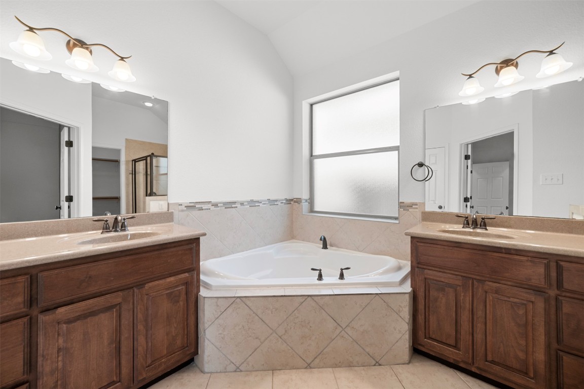 216 Archipelago Trail Austin, TX 78717 - Photo 27 of 40 Bathroom featuring two vanities, a garden tub, light tile patterned floors, a stall shower, and lofted ceiling