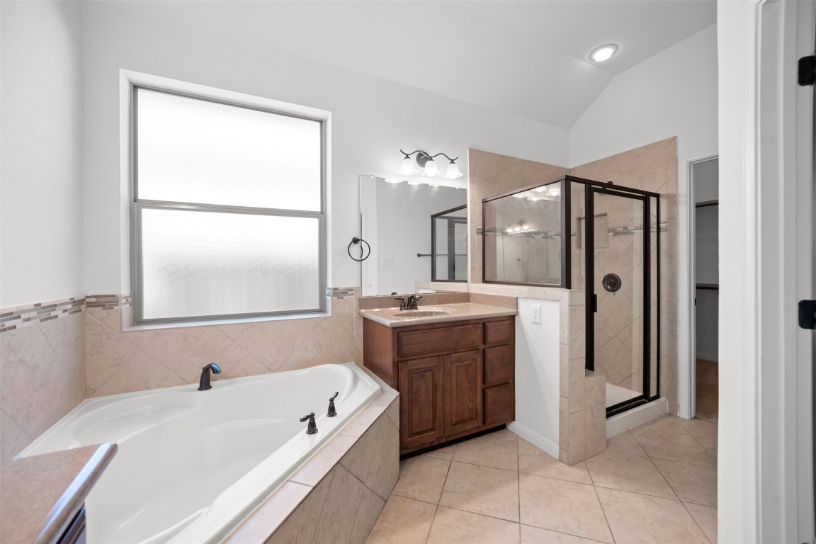 216 Archipelago Trail Austin, TX 78717 - Photo 28 of 40 Bathroom featuring vanity, a stall shower, a bath, light tile patterned floors, and lofted ceiling